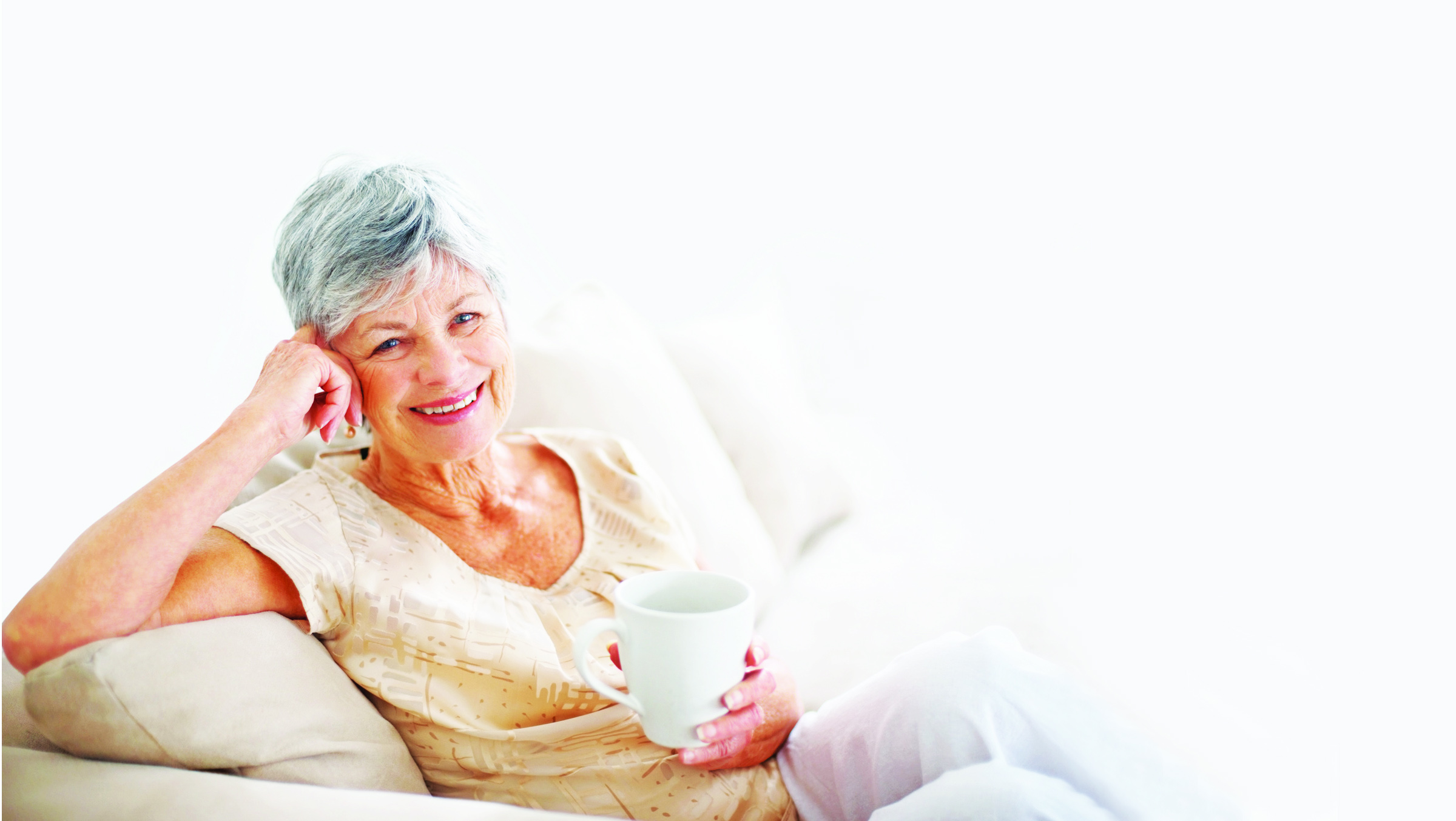 Smiling old woman drinking coffee while at home
