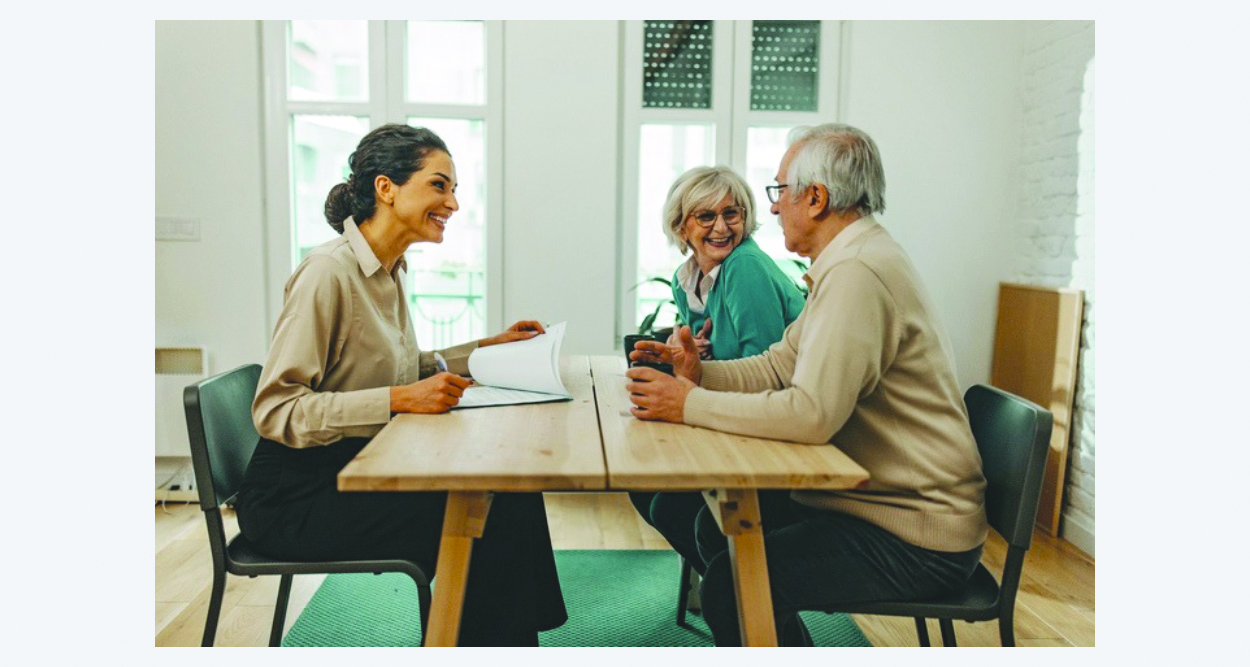 Senior couple meeting with a smiling female insurance agent across a table.