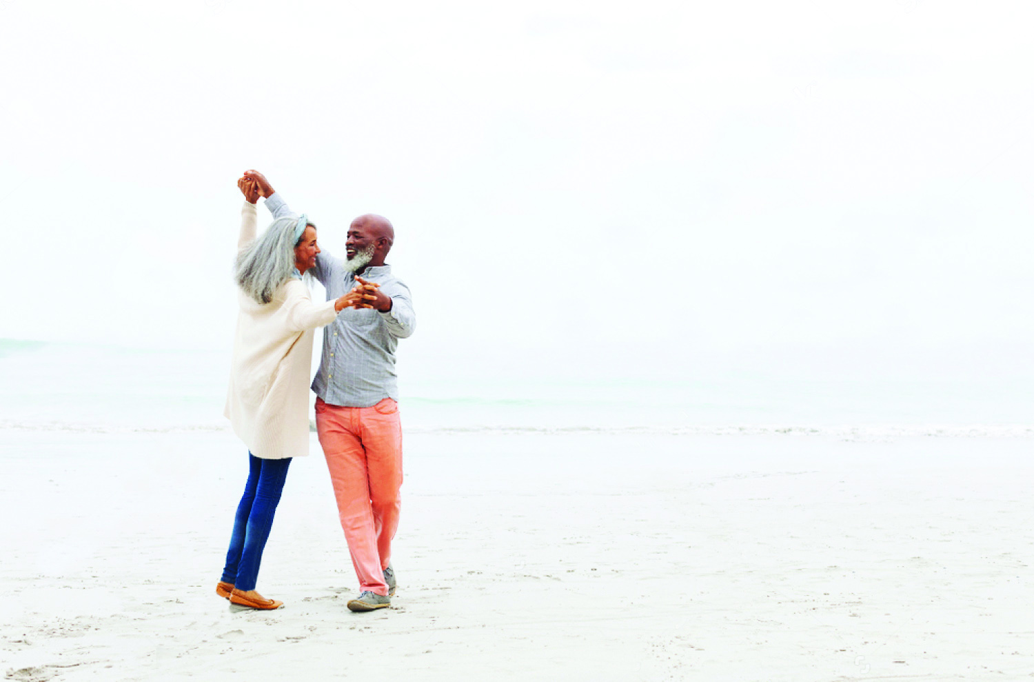 Happy senior couple stays active by dancing on the beach