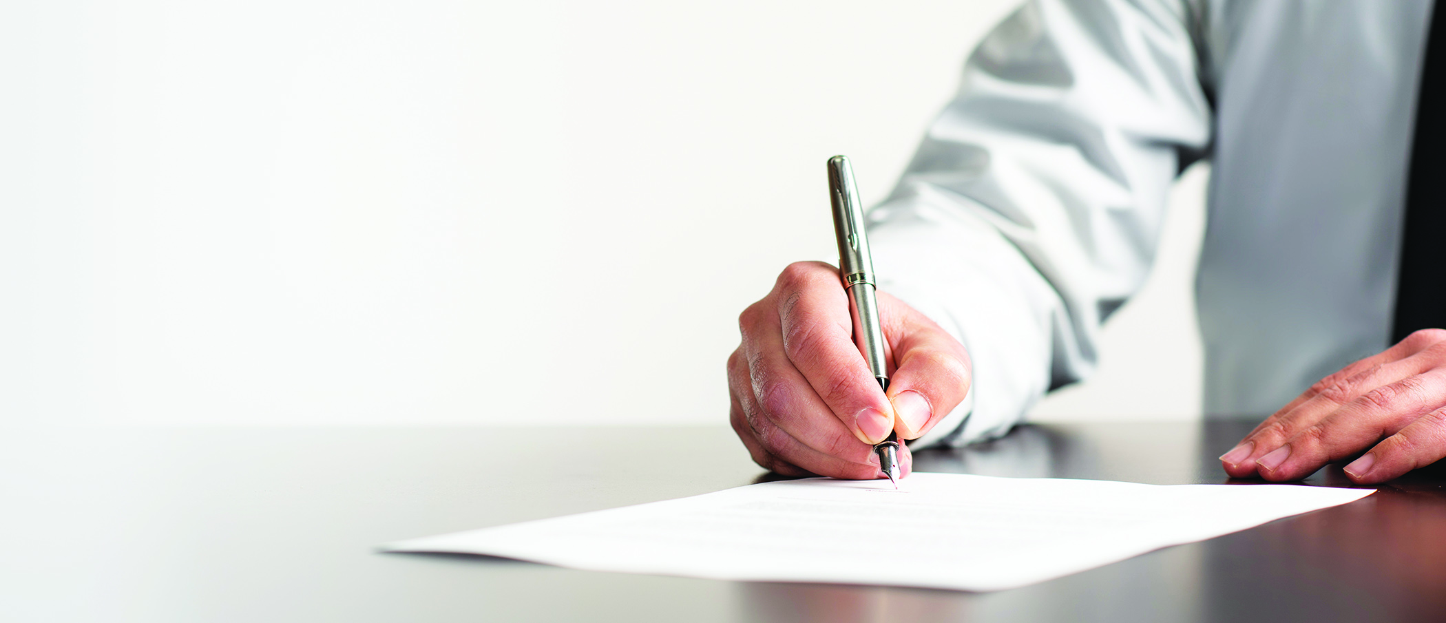 Man in a white shirt and tie signing a legal document