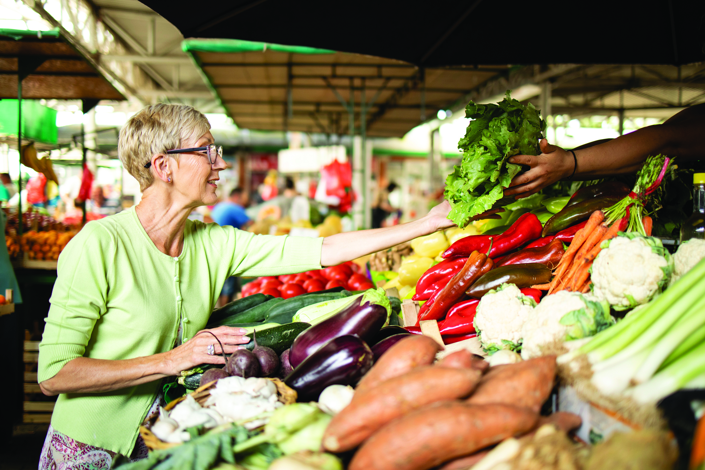 Older woman selecting fresh vegetables at a farmers market