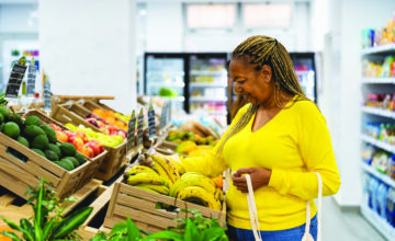 Older woman selecting fresh bananas and produce in a grocery store