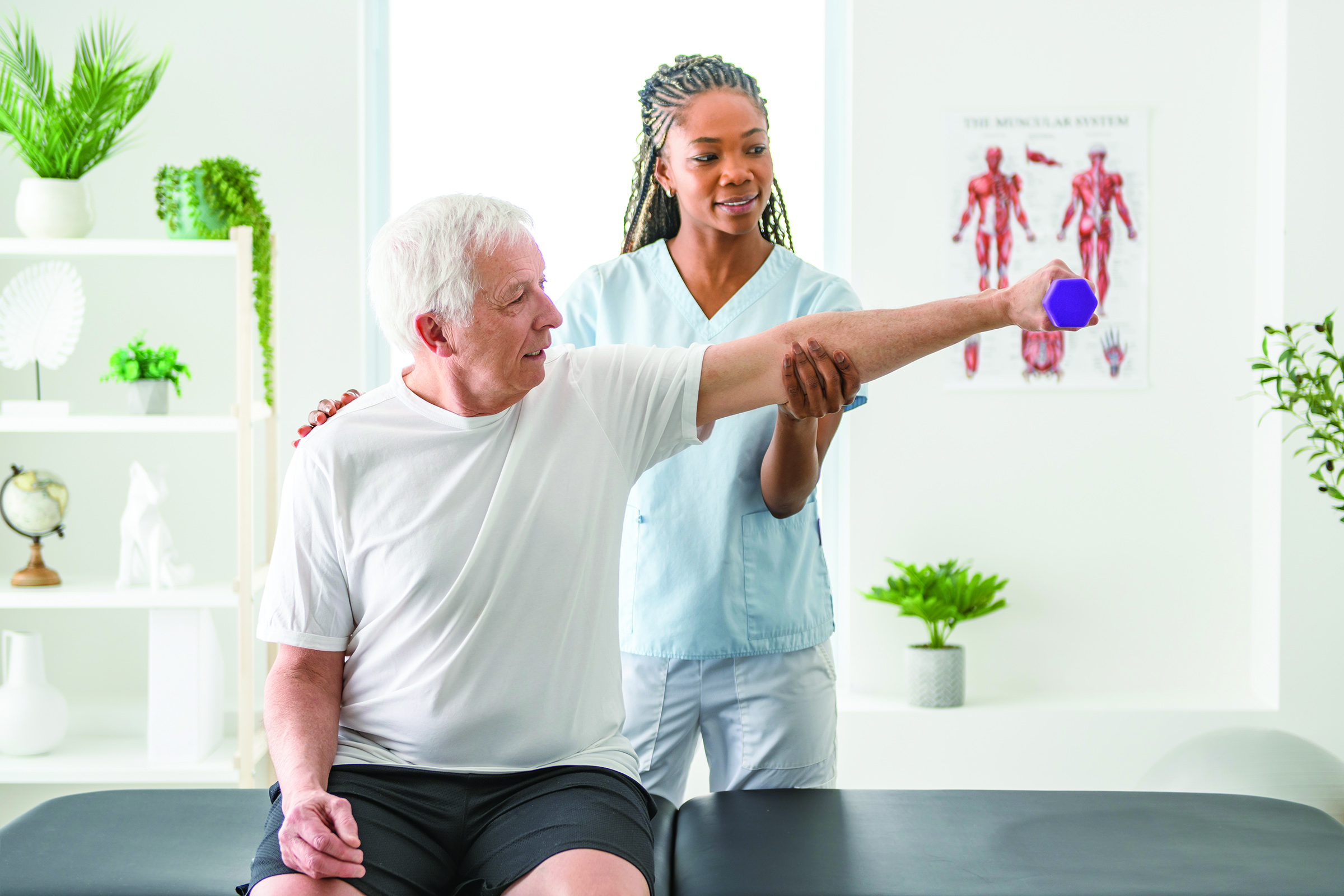 Senior man in physical therapy lifting a weight with assistance from a therapist.
