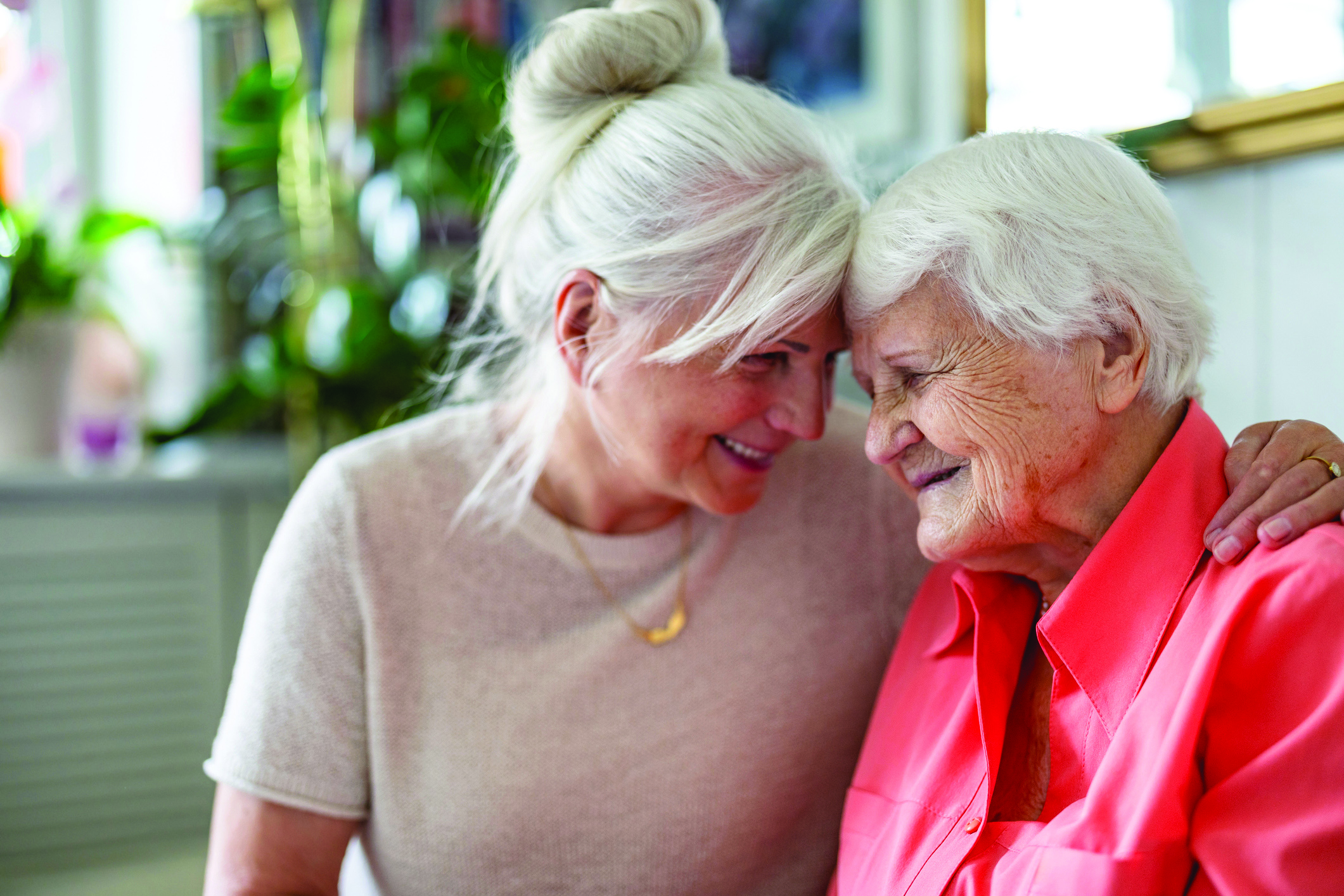 Adult daughter gently comforting elderly mother with dementia in a warm home setting