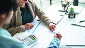 Two people reviewing financial documents and tax paperwork at a desk