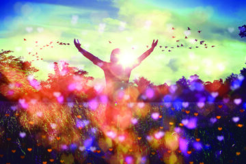 A person standing outside on a sunny day with arms raised, surrounded by birds, trees, and sunlight.